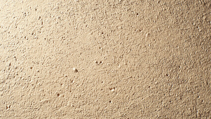 Close-up of a rough, light beige textured surface, possibly stucco or concrete, featuring numerous small pores and granular imperfections, ideal for a background.