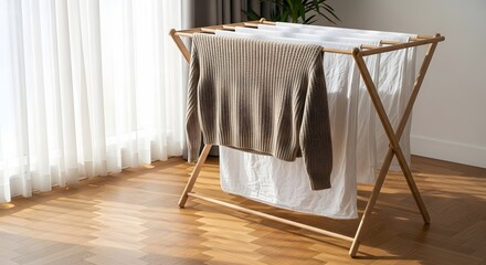 Fresh laundry drying naturally on a wooden clothes rack by a sunlit window for an energy-saving concept and sustainable home care