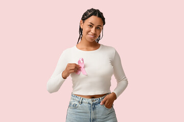 Young African-American woman with pink ribbon on color background. Breast cancer awareness concept