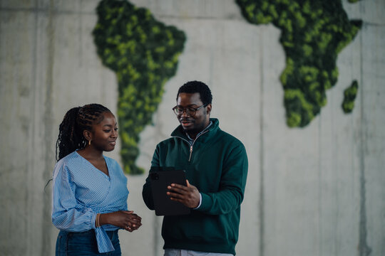 Coworkers discussing global business strategy with tablet