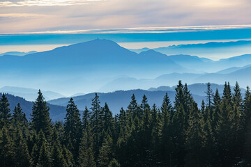 Panoramic view of the Kamnik-Savinja Alps and surrounding valleys submerged in a dense layer of atmospheric inversion fog at sunrise.