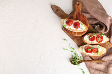Wooden boards of tasty tomato bruschetta with ricotta and microgreens on white background
