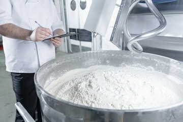 Dough mixing process in confectionery production line by caucasian male adult technologist