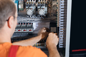 Back view worker technician adjusting industrial control panel in factory