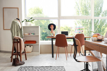 Interior of fashion designer's studio with workplace, mannequins and shelf unit