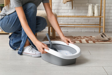 Woman with litter box for cat on floor in room