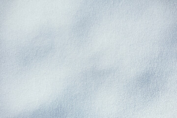Snow texture. Brilliant, sparkling snow surface with delicate ice crystals and soft blue shadows. Sunlight catches the textured fresh snow, creating a cold, ethereal winter backdrop