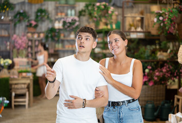 Married couple look for something in room garden furniture store, searching for perfect item to complete patio. Woman with husband buyers looks around in showroom