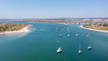 Scenic coastal view featuring boats anchored in tranquil waters, surrounded by lush greenery and sandy shores, ideal for relaxation and leisure. Tavira Portugal Algarve