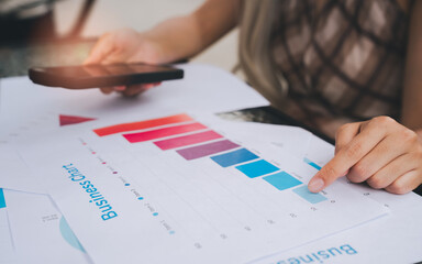 Business chart with colorful bar graph and person pointing on data using smartphone for analysis and planning