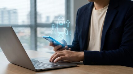 A person in a dark suit uses a smartphone with a glowing rocket icon and upward arrows appearing above alongside a laptop on a wooden desk Startup Business Success Growth Technology