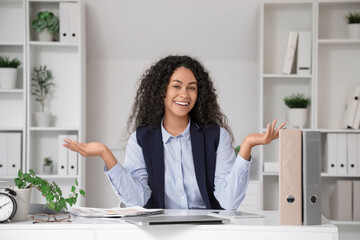 Young African-American businesswoman video chatting at table in office