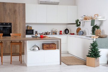 Interior of festive kitchen with white counters, Christmas decorations and fir tree