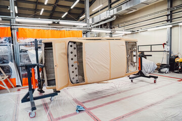 Specialist spraying anti rust sealant into the hidden chassis cavities. Protection against corrosion and internal body element sealing in a professional auto service shop