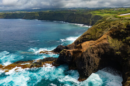 Aerial drone view of rugged volcanic cliff on Atlantic coastline Sao Miguel Azores - Powered by Adobe