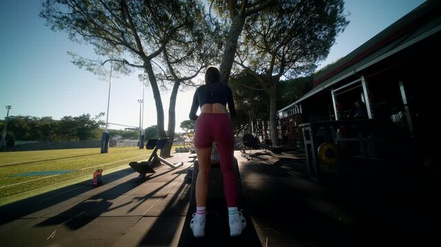 Sunlit scene of athlete attaching weight to sled during warmup