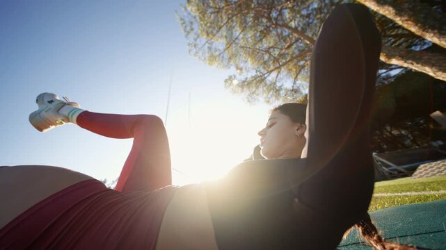 Sunlit park with woman performing abdominal exercises calmly