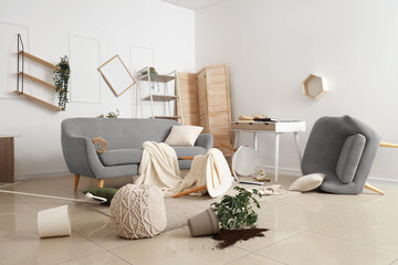 Fototapeta premium Interior of messy living room with sofa, overturned table and broken things after earthquake