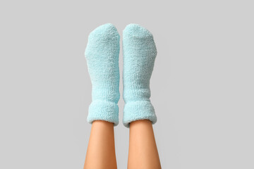 Legs of young woman in warm blue socks on grey background