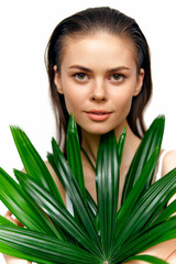 Naklejka premium Beautiful woman holding palm leaves, showcasing natural beauty and calmness with a bright background, perfect for wellness and eco-friendly themes.