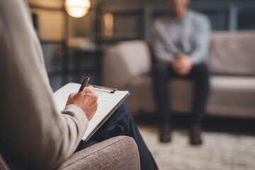 close up of professional therapy session, friendly psychologist or therapist writing notes during consultation with patient