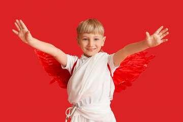 Obraz premium Cute little happy boy dressed as cupid on red background. Valentine's Day celebration