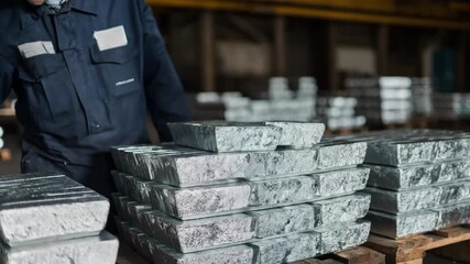 Medium shot showing a technician stacking polished ingots methodically on a pallet for organized transport to the melting furnace