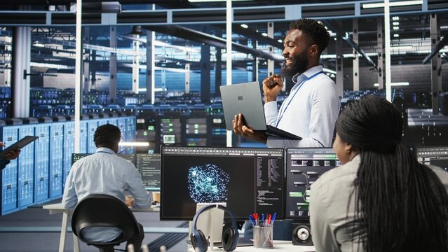 Happy data center admin uses node tree programming on laptop, doing high five with coworker. Smiling server farm worker greeting colleague, reviewing data analysis graph, camera A