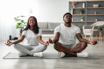 Fotobehang Lotusbloem Domestic Yoga. Happy young black couple meditating with closed eyes at home in lotus position, millennial lady and guy sitting on fitness mat on the floor in living room, enjoying healthy lifestyle  © Prostock-studio