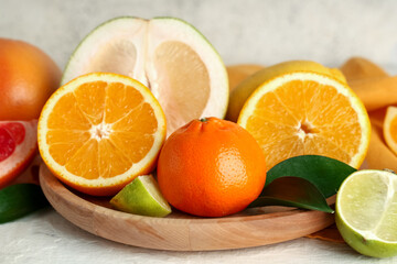 Wooden tray with tasty citrus fruits on white background, closeup