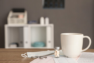 Cup of coffee with pills and cardiograms on medical student's table in clinic, closeup