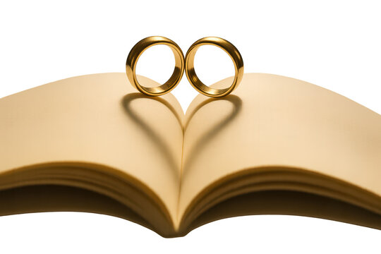 Two golden wedding rings on an open book with transparent background show love