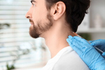 Young man receiving injection for hair growth in clinic, closeup