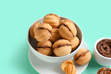 Bowl of sweet walnut shaped cookies with boiled condensed milk on turquoise background