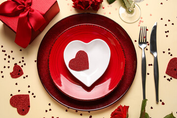 Beautiful table setting with gift box, hearts and red roses on yellow background. Valentine's Day celebration