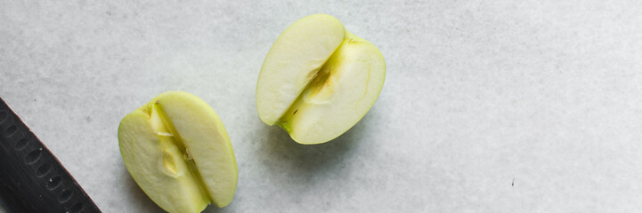 Top view of green apples being sliced on a marble countertop