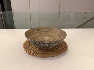 Woven Home Decor: Handmade natural fiber bowl and placemat arranged on a sleek white countertop in a minimalist modern kitchen.