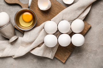 Holder with raw chicken eggs on grey background