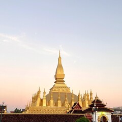 Fototapeta premium an important place located in the centre of vientiane and is also a popular tourist attraction. evening photos with a golden sky with sunlight and beautiful golden that luang