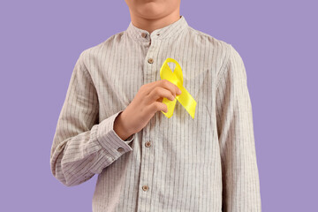 Little boy with childhood cancer awareness ribbon on lilac background, closeup