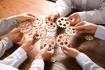 Obraz premium Group of business people holding wooden gears at table