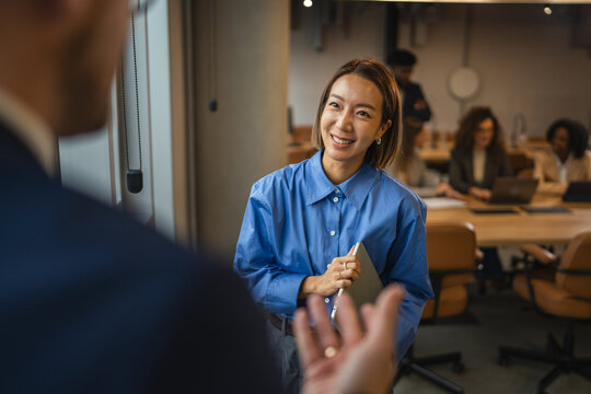 Asian businesswoman discussing project with colleague in modern office
