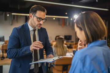 Businessman explaining document to female colleague in office