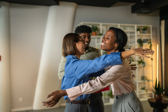 Diverse colleagues greeting and hugging in modern office - Powered by Adobe