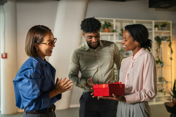 Diverse colleagues celebrating a happy work anniversary receiving a gift