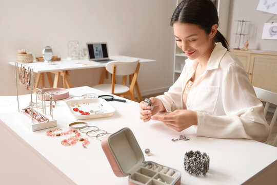 Female jewelry designer examining adornment in workshop