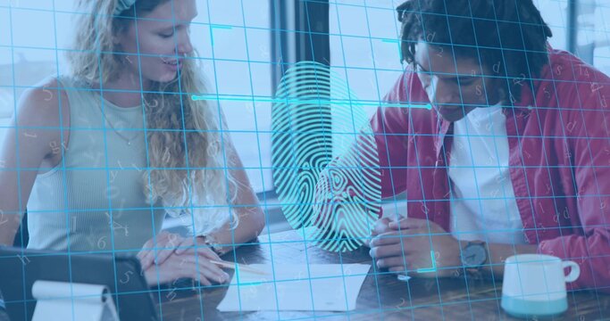 Reviewing pair wearing red jacket leaning over forms at office table by window, showing fingerprint