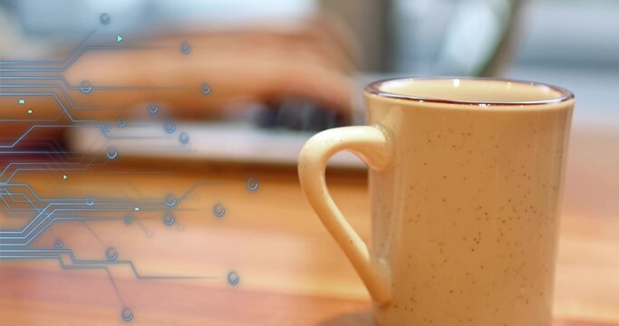 Sitting speckled beige ceramic mug on wood table, blurred laptop hands and blue circuit, copy space