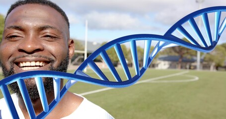 Smiling man in white shirt posing on sports turf with blue DNA helix overlay, copy space