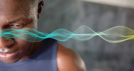 Gazing male athlete wearing navy sleeveless top at studio, with waveform graphic, copy space